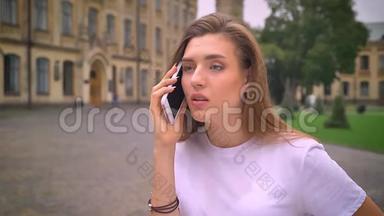美丽的白种人自信的女孩<strong>专注</strong>于她的电话，交谈和站在旁边，没有旧城市的背景